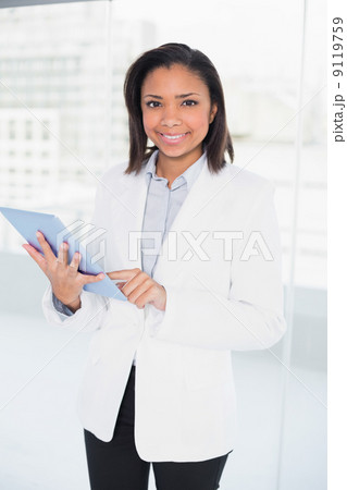Pleased young dark haired businesswoman using a tablet pc Pleased young dark haired businesswoman using a tablet pc 9119759