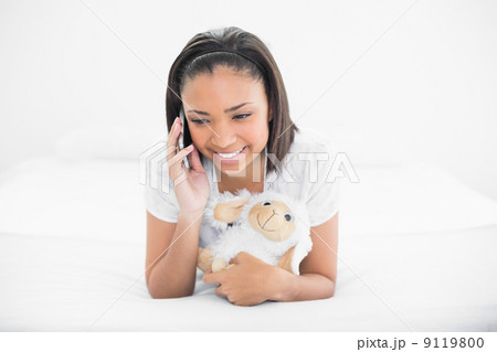 Cheerful young dark haired model making phone call while cuddlin 9119800