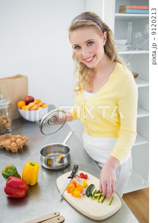 Smiling cute blonde putting vegetables in a pot 9120213