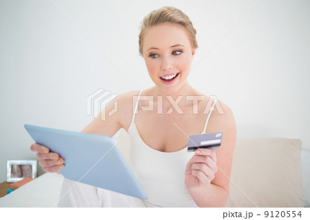 Natural cheerful blonde holding tablet and credit card 9120554