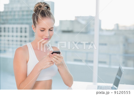Smiling sporty blonde sending a text 9120555