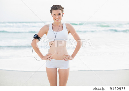 Cheerful slim brown haired model in white sportswear listening t 9120973