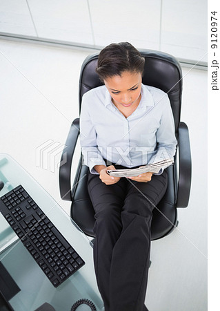 Cute young dark haired businesswoman reading a newspaper 9120974
