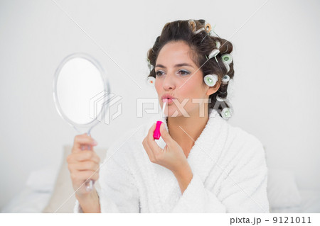 Calm natural brunette applying lip gloss 9121011
