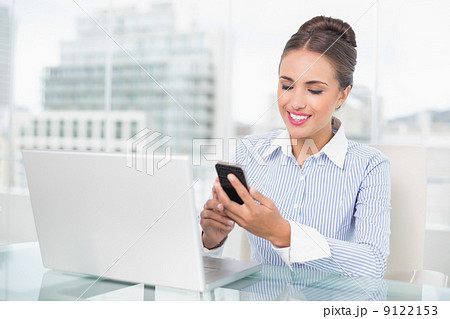 Smiling brunette businesswoman looking at smartphone 9122153