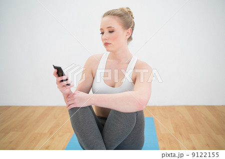Attractive sporty blonde looking at smartphone 9122155