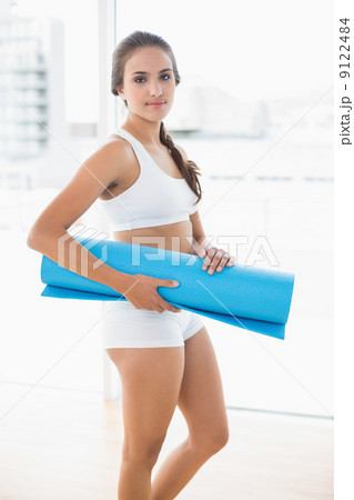 Content sporty brunette holding an exercise mat Content sporty brunette holding an exercise mat 9122484