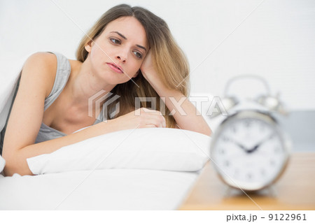 Tired young woman lying under the cover on her bed Tired young woman lying under the cover on her bed 9122961