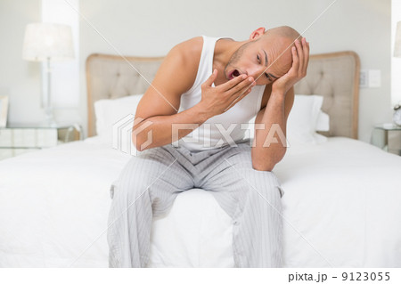 Bald man sitting and yawning in bed 9123055