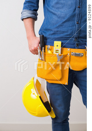 Mid section of a handyman with toolbelt and hard hat 9124899