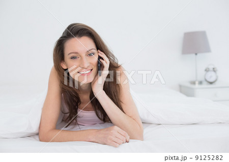 Portrait of a smiling woman using mobile phone in bed Portrait of a smiling woman using mobile phone in bed 9125282
