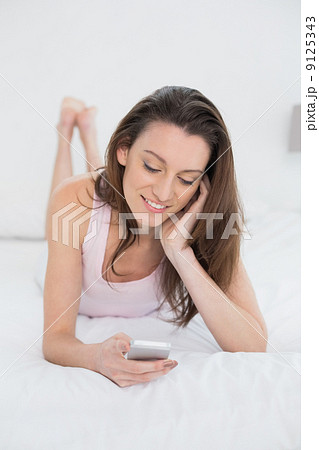 Relaxed happy woman looking at mobile phone in bed Relaxed happy woman looking at mobile phone in bed 9125343
