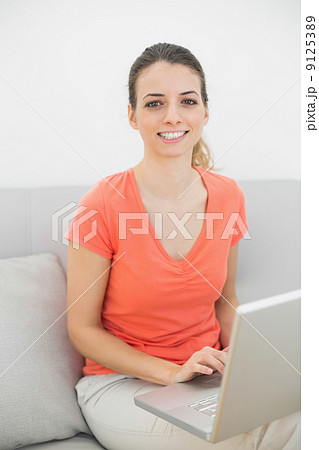Smiling brunette woman working with her notebook looking at came 9125389