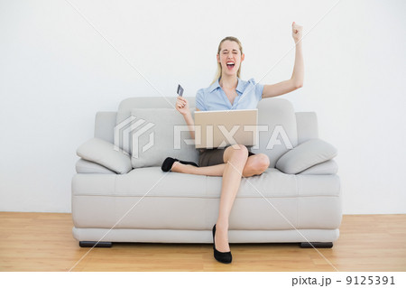 Pretty cheering businesswoman online shopping with her notebook 9125391
