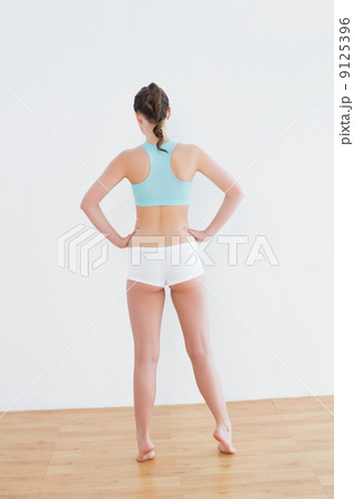 Rear view of toned woman standing against wall 9125396