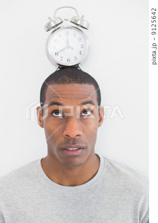 Close up of a man with an alarm clock on top of his head Close up of a man with an alarm clock on top of his head 9125642
