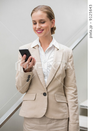 Smiling stylish businesswoman holding smartphone Smiling stylish businesswoman holding smartphone 9125643