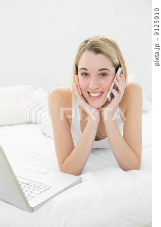 Attractive peaceful woman lying on her bed while phoning Attractive peaceful woman lying on her bed while phoning 9125910