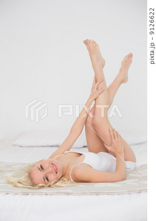 Smiling young woman in nightwear lying in bed Smiling young woman in nightwear lying in bed 9126622