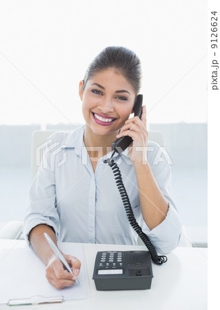 Portrait of an elegant businesswoman using telephone at desk 9126624