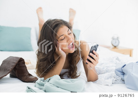 Woman shouting into mobile phone in bed 9126765