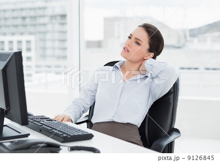 Businesswoman with neck pain sitting at desk Businesswoman with neck pain sitting at desk 9126845