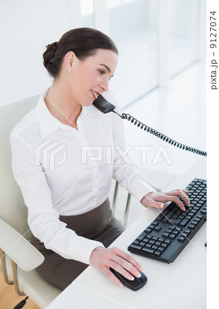 Businesswoman using computer and telephone in office 9127074