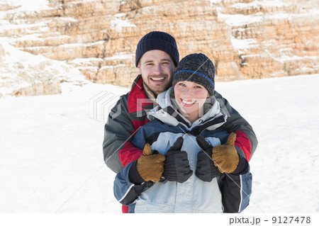 Happy loving couple gesturing thumbs up on snow 9127478