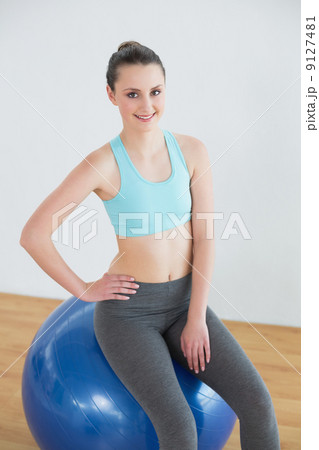 Fit woman sitting on exercise ball in fitness studio 9127481