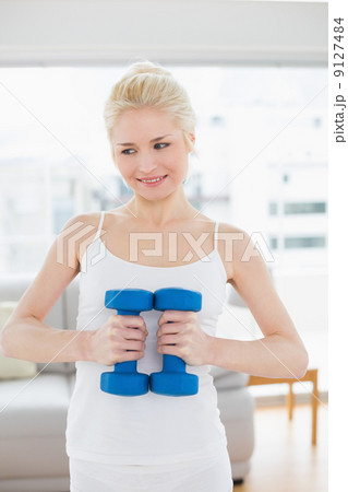 Thoughtful woman with dumbbells at fitness studio 9127484