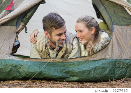 Smiling couple lying in tent after a hike 9127485