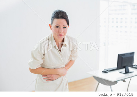 Businesswoman suffering from stomach pain in office Businesswoman suffering from stomach pain in office 9127619