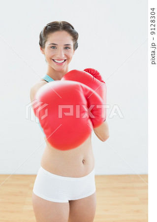 Beautiful woman in red boxing gloves at fitness studio 9128304