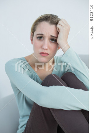 Natural young woman sitting worried on couch 9128416