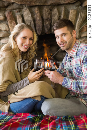 Couple toasting wineglasses in front of lit fireplace 9128651