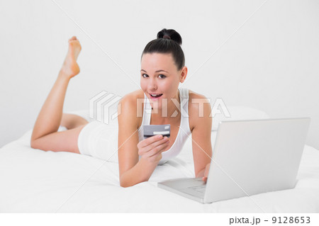 Casual woman doing online shopping in bed 9128653