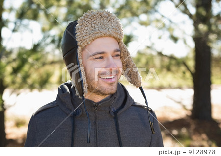 Smiling man in warm clothing looks to his side in forest 9128978