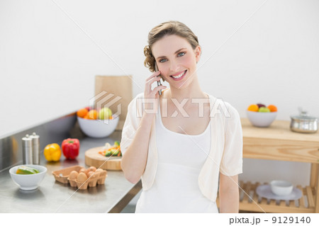 Content young woman honing while standing in kitchen 9129140