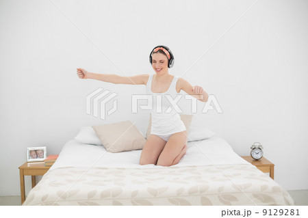 Pretty woman moving on her bed while listening to music 9129281