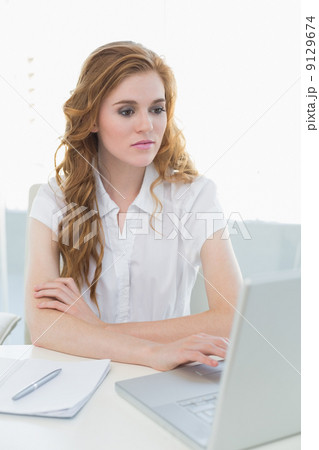 Serious businesswoman using laptop at office 9129674