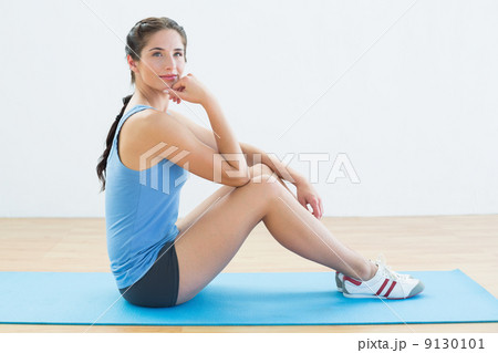 Fit woman sitting upright on exercise mat 9130101