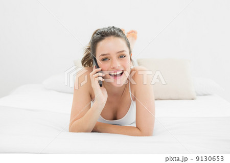 Portrait of a casual woman using mobile phone in bed Portrait of a casual woman using mobile phone in bed 9130653
