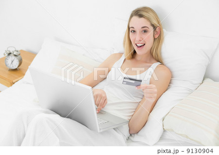 Astonished young woman using her laptop for home shopping while Astonished young woman using her laptop for home shopping while 9130904