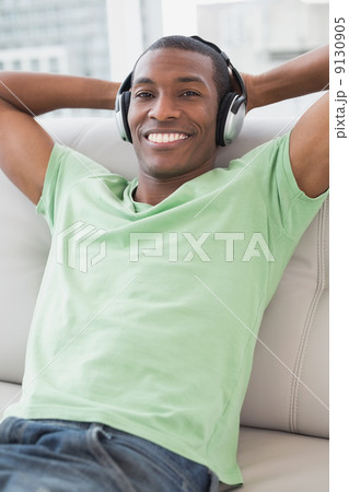 Relaxed Afro man with headphones sitting on sofa 9130905