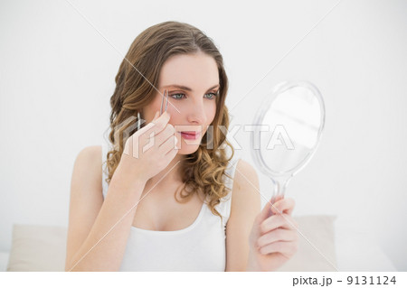 Woman plucking her eyebrows 9131124