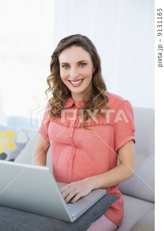 Beautiful pregnant woman working with her notebook sitting on a Beautiful pregnant woman working with her notebook sitting on a 9131165