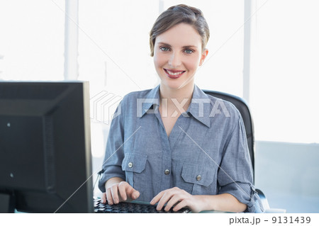 Content businesswoman working on computer at her desk Content businesswoman working on computer at her desk 9131439
