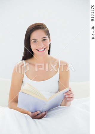Portrait of a smiling woman with book in bed 9131570