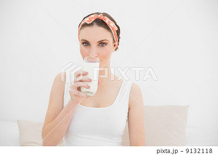 Woman drinking a glass of milk looking into the camera 9132118