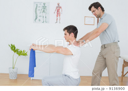 Male therapist assisting young man with exercises 9136900